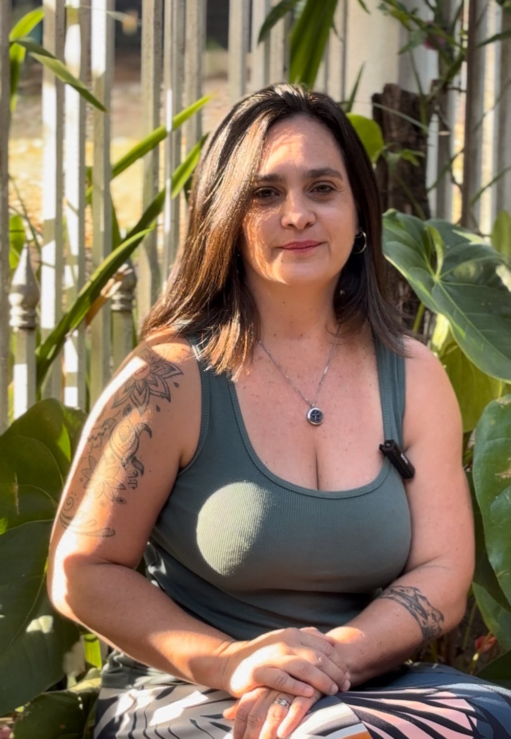 Ana Sofia Lamas, criadora do Corpo Vital, sentada ao ar livre entre plantas, sorrindo levemente.